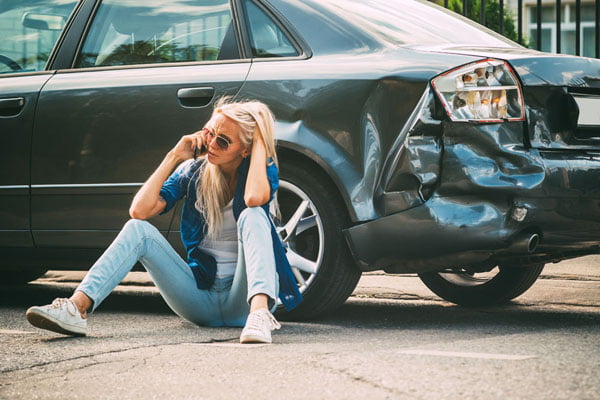 The girl sits at the broken car